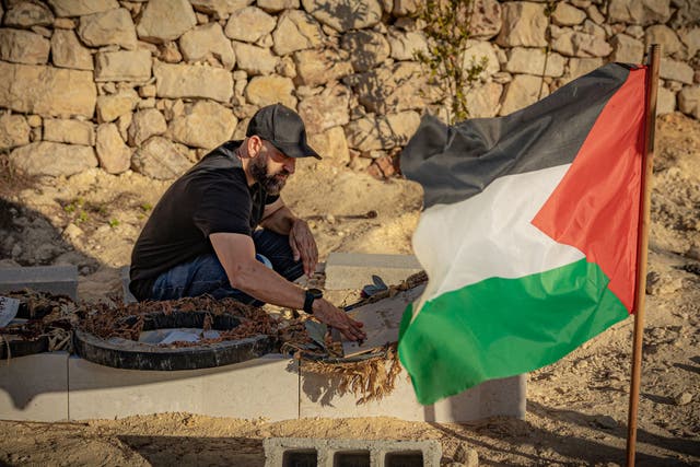 <p>Kamel Musallet, the father of a US citizen killed by settlers, prays by his son's grave in the West Bank</p>