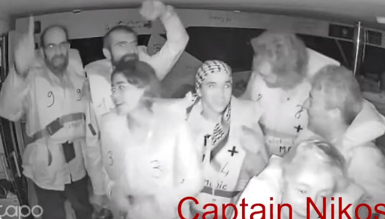 Activists wave at the camera on board the Captain Nikos