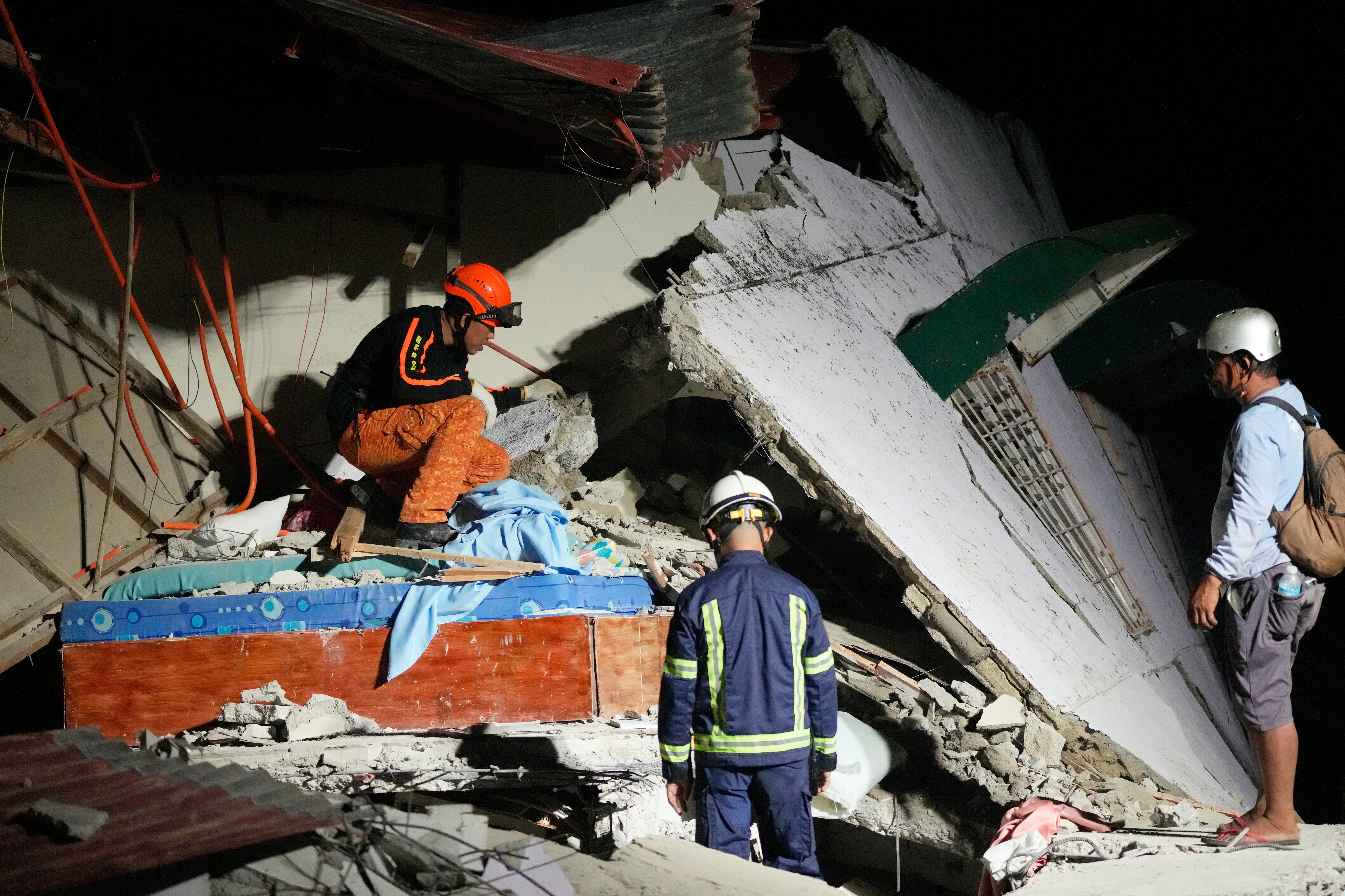 <p>Rescuers check for survivors in the ruins of a collapsed building, after a strong earthquake struck Bogo city, Cebu Province, Central Philippines</p>