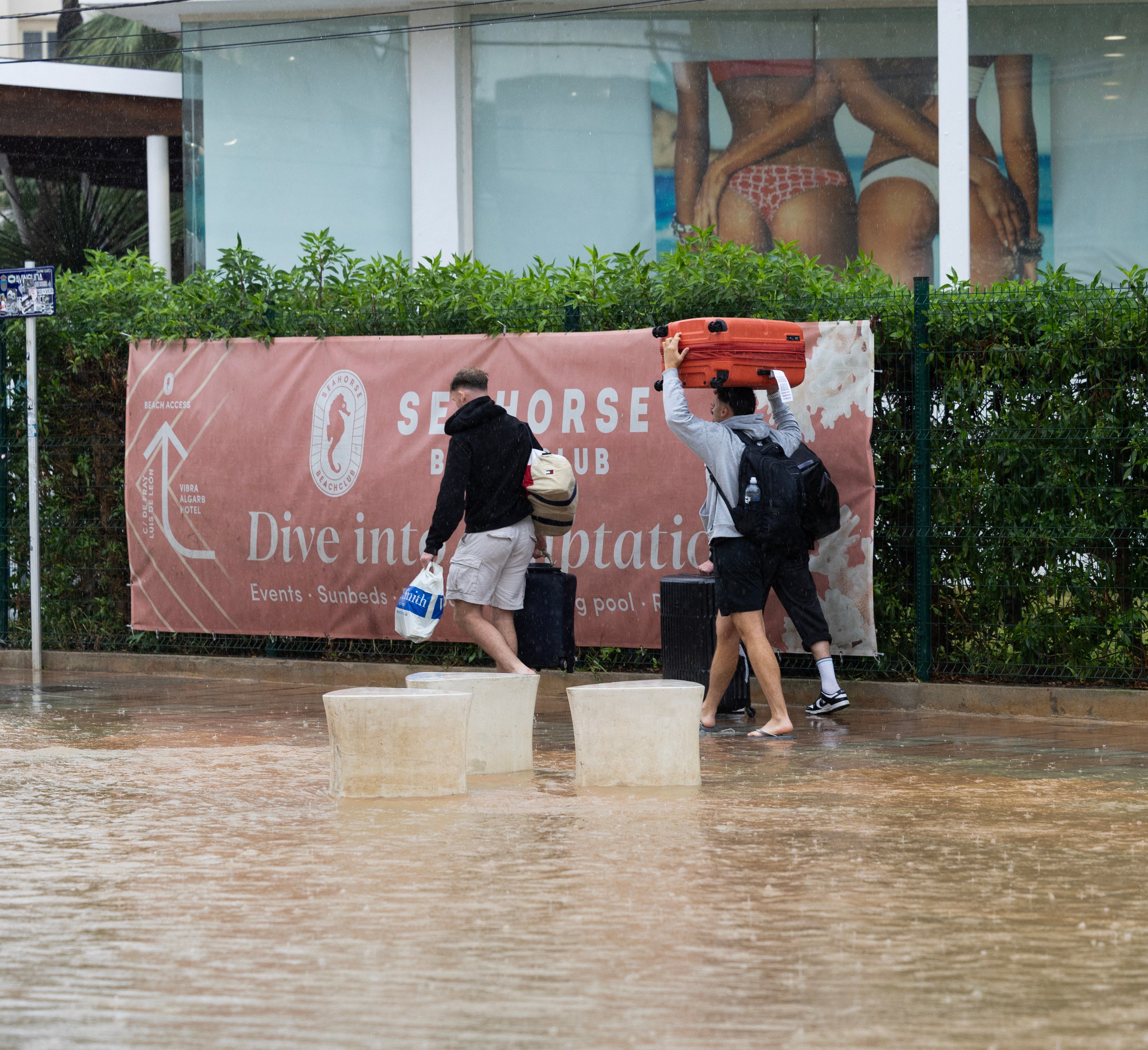 Tourists walk through a flooded street in Ibiza on September 30, 2025