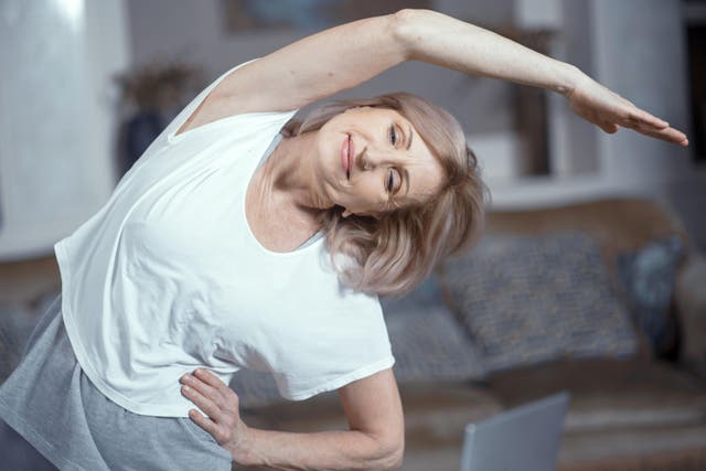 <p>Middle aged woman doing yoga at home</p>