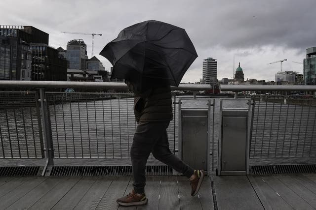 A person struggles with their umbrella (Brian Lawless/PA)