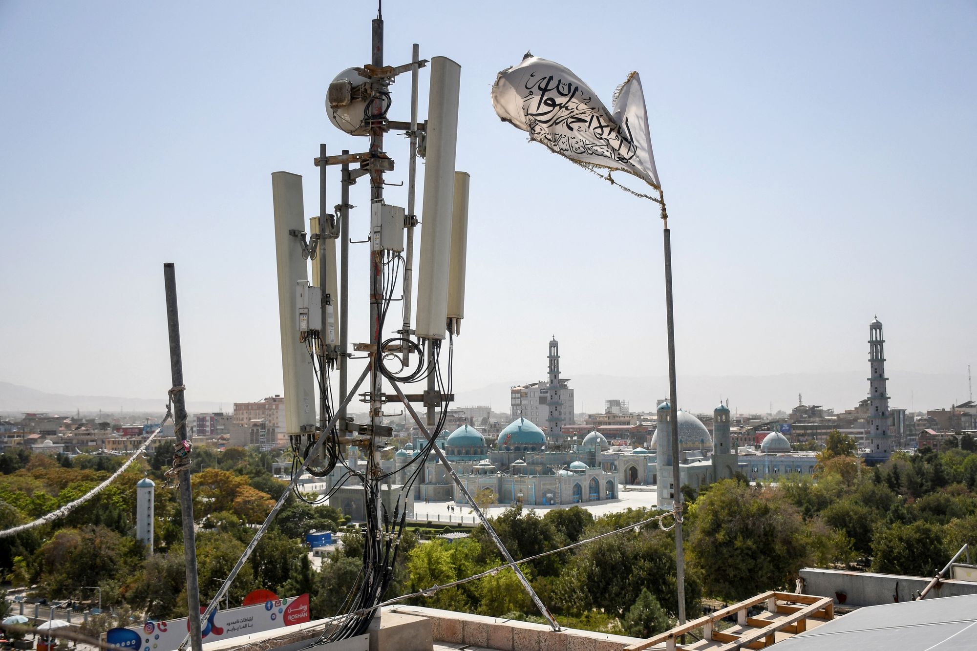 A Taliban flag flutters near telecom equipment