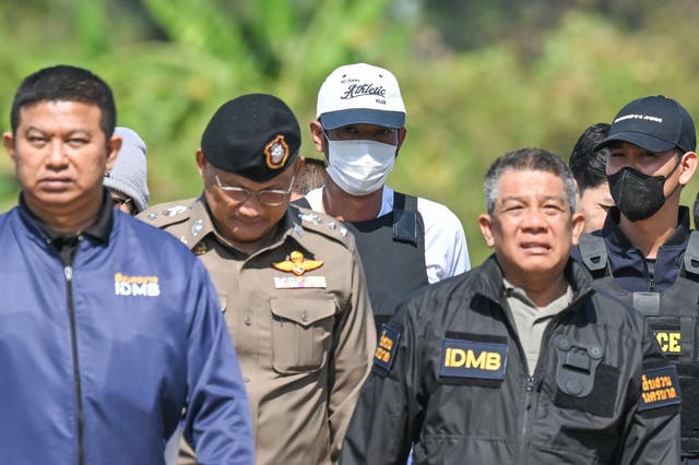 <p>Thai police officers escort Ekkalak Pheanoi, centre, the accused in the shooting of Cambodian politician Lim Kimya, after he was deported from Cambodia, in Bangkok, Thailand, on 11 January 2025</p>