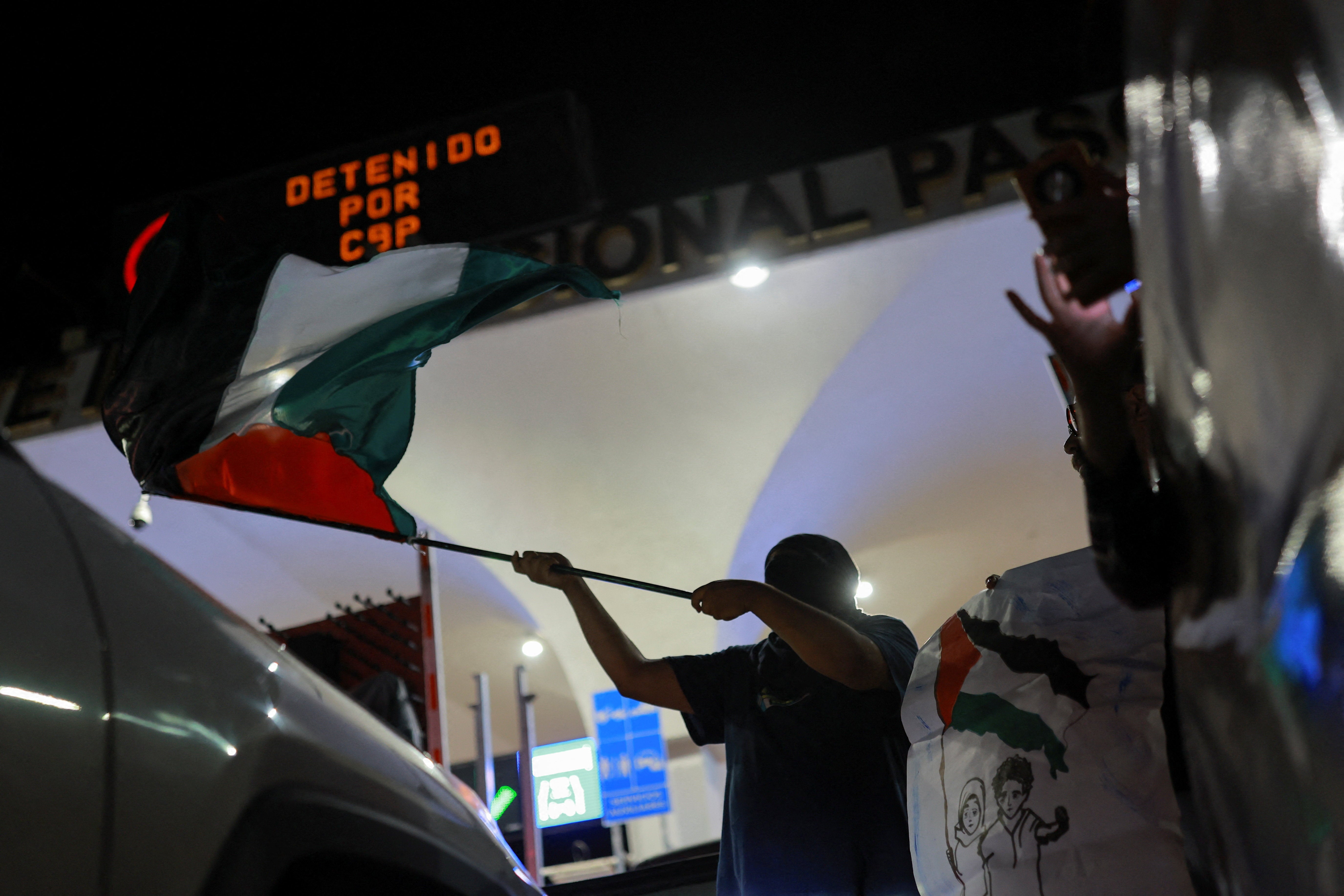 A pro-Palestinian demonstrator waves a Palestinian flag during a protest to condemn the Israeli forces' interception of some of the vessels of the Global Sumud Flotilla aiming to reach Gaza and break Israel's naval blockade, at the Paso del Norte International Bridge in Ciudad Juarez, Mexico