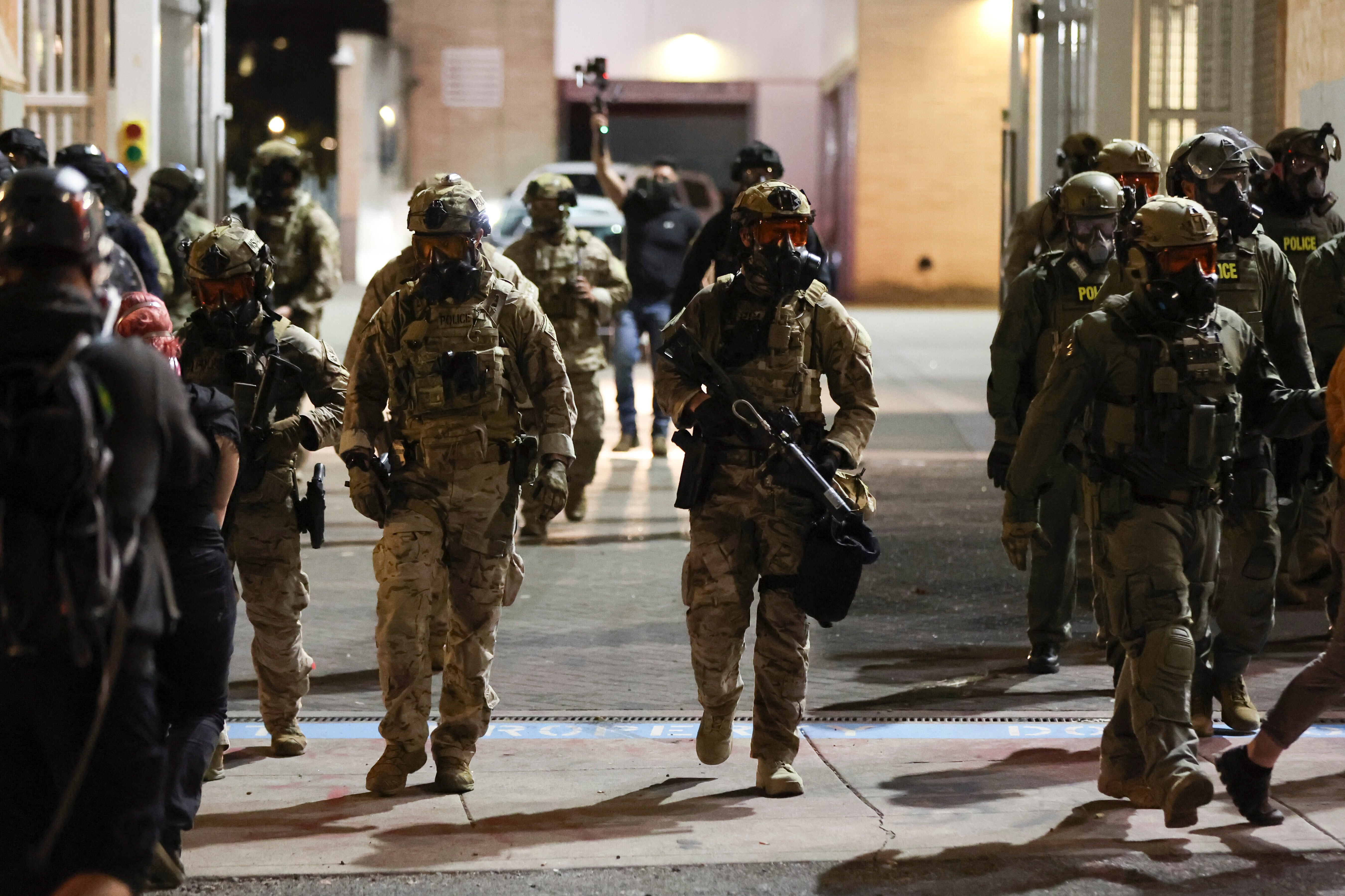 Federal agents walk into the street as people protest outside a U.S. Immigration and Customs Enforcement facility in Portland, Oregon, Friday, October 3