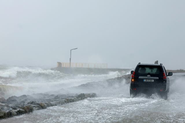 <p>A person drives their car drives on a footpath as the road is flooded during Storm Amy which brought severe weather, in Galway, Ireland</p>