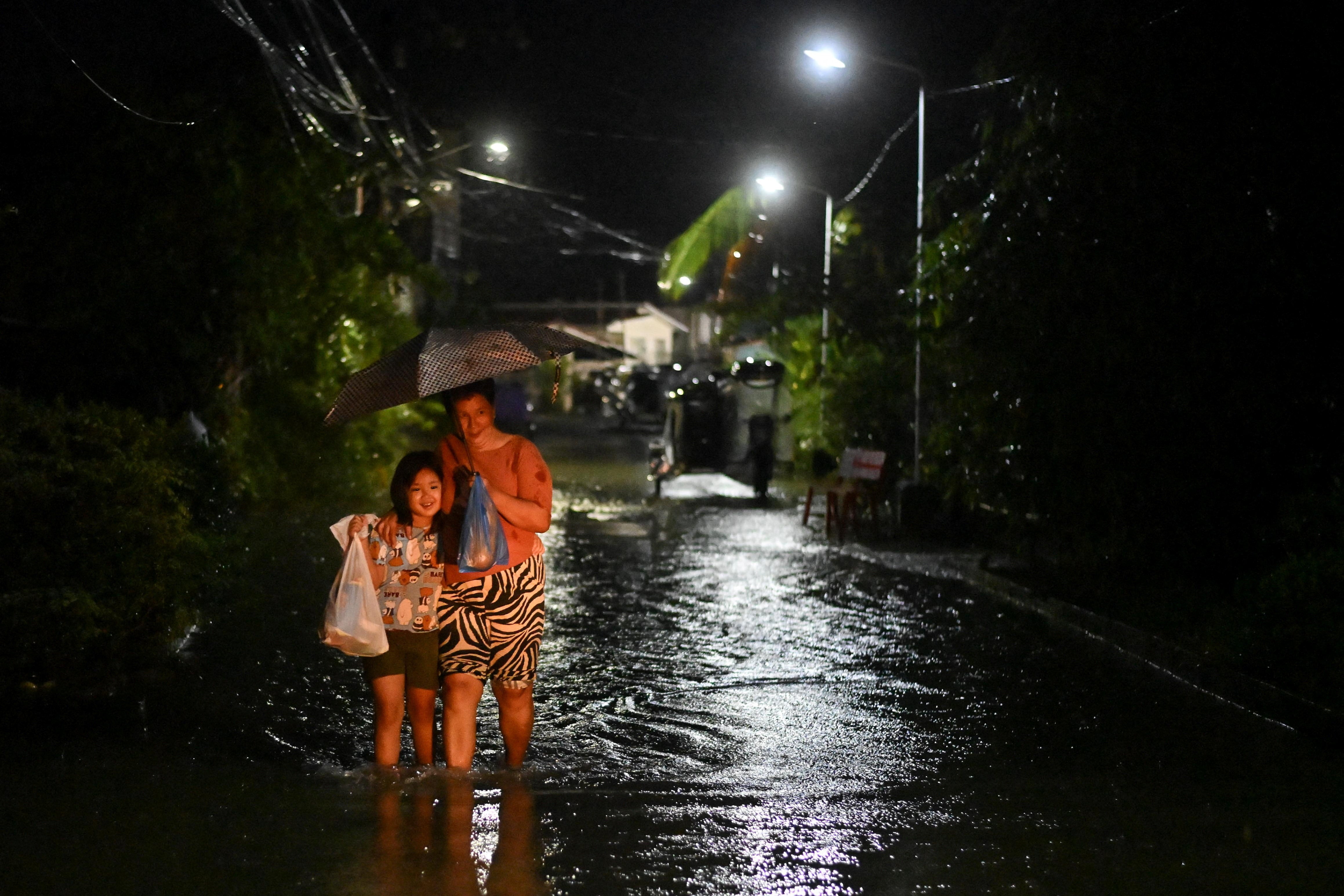 People wade through a flooded street following rain, intensified by Severe Tropical Storm Matmo, in Santa Lucia, Calumpit, Bulacan province, Philippines