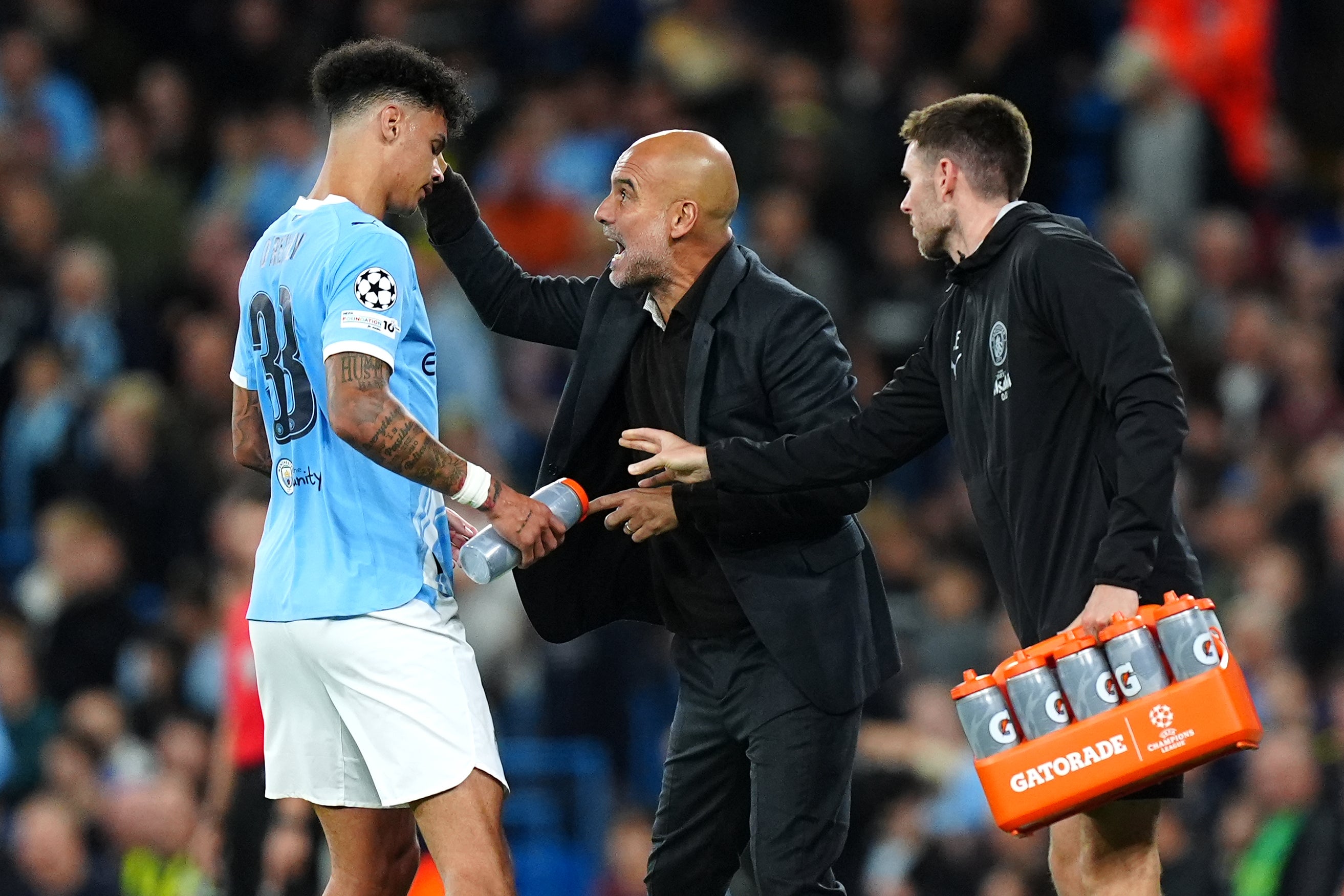 <p>Manchester City manager Pep Guardiola (centre) speaks with player Nico O'Reilly (left)</p>