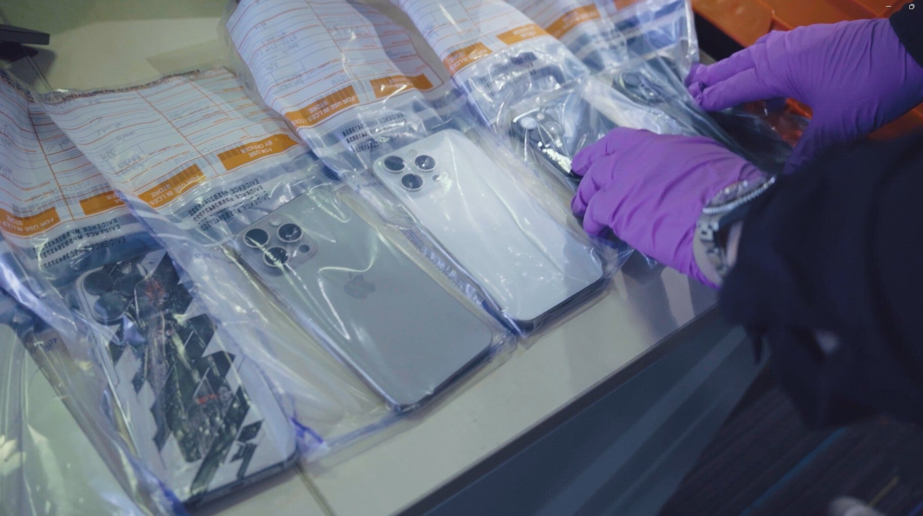 <p>An officer examining the stolen phones recovered during Operation Echosteep (Metropolitan Police/PA)</p>