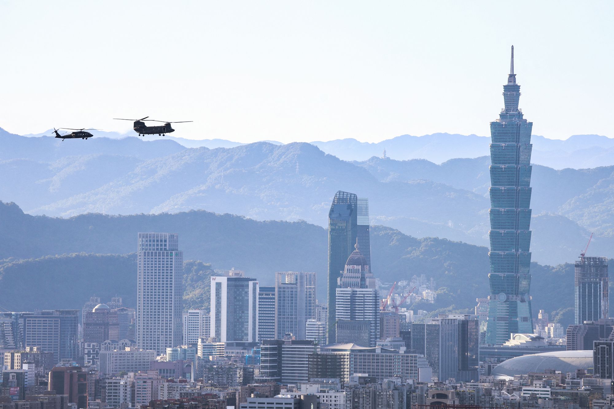 A Sikorsky UH-60M Black Hawk helicopter (L) and a Boeing CH-47SD Chinook tandem-rotor helicopter perform a flyby past the Taipei 101 building as part of rehearsals ahead of Taiwan's National Day