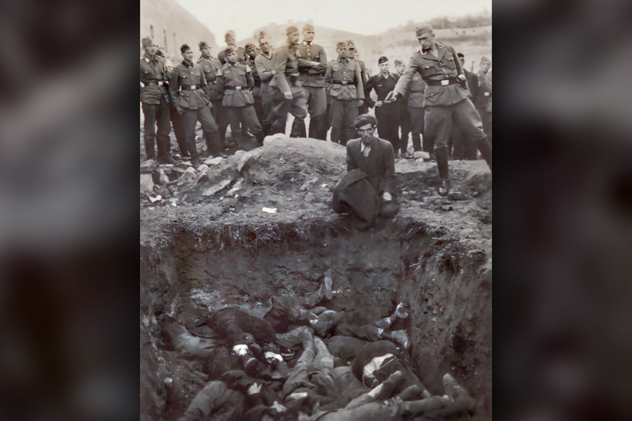 <p>An SS sergeant pictured preparing to shoot a Jewish prisoner by a mass grave in Ukraine in 1941</p>