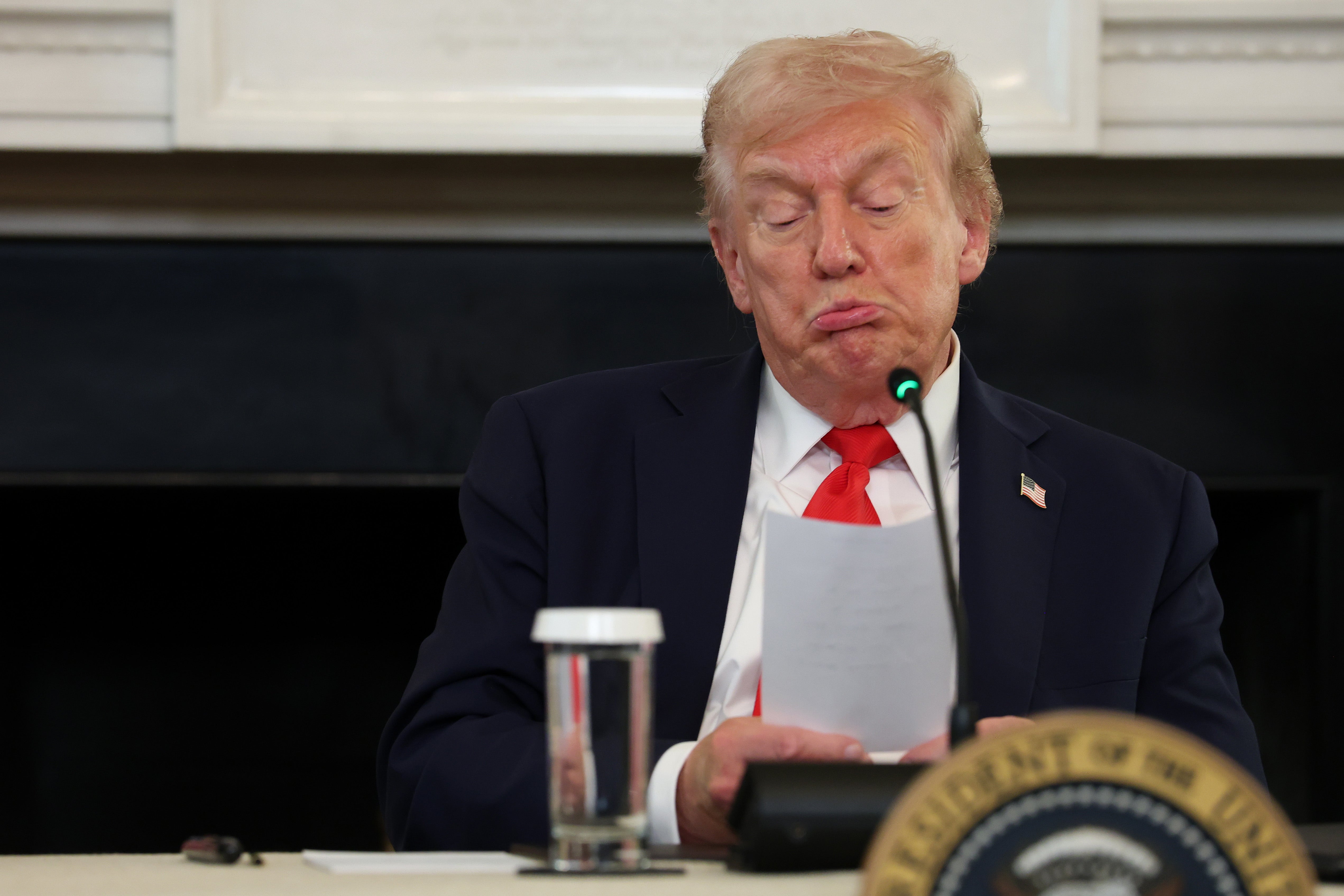 President Donald Trump reads a note handed to him by U.S. Secretary of State Marco Rubio he said was regarding Middle East peace talks during a roundtable discussion in the State Dining Room of the White House on October 08, 2025