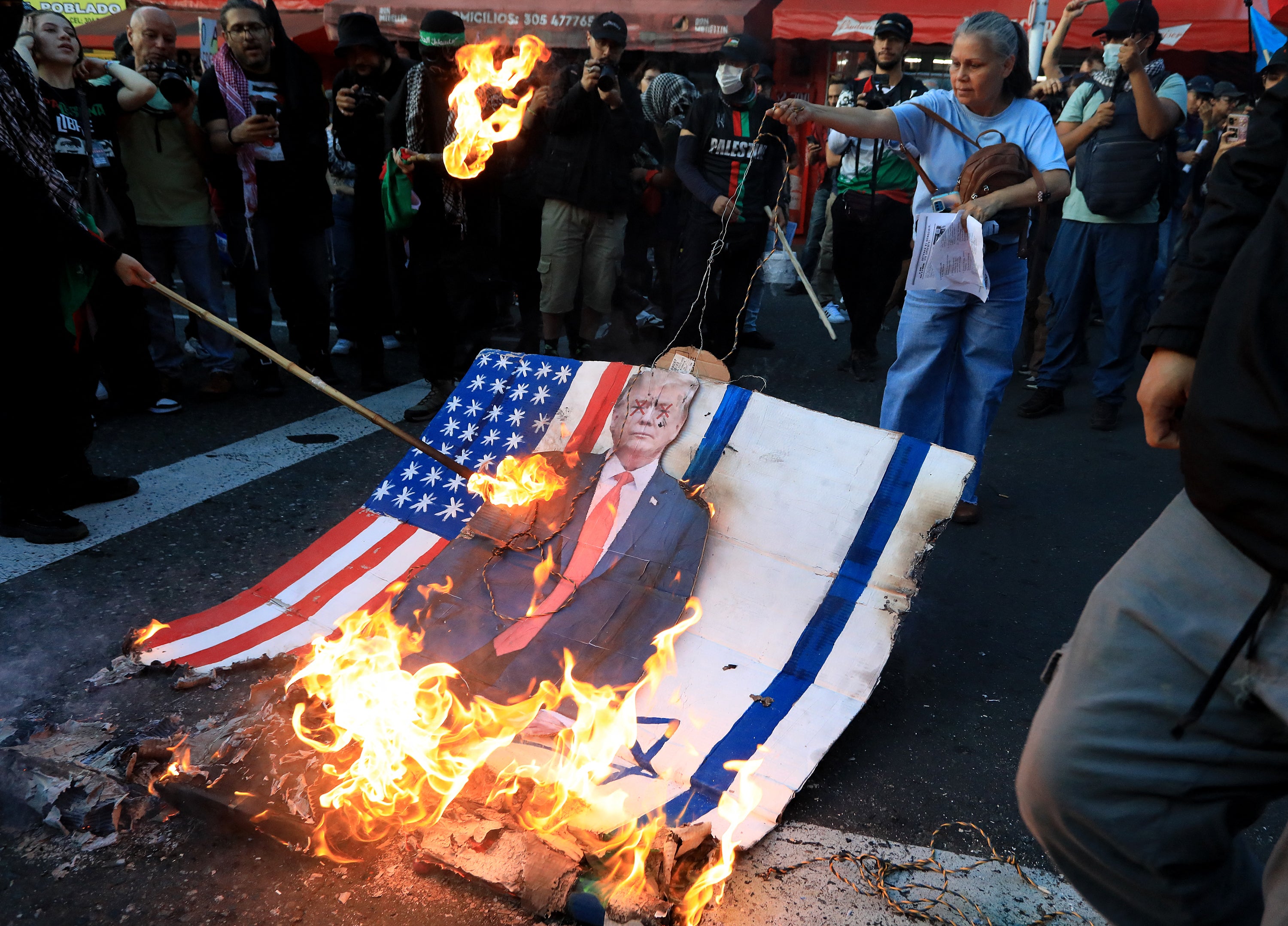 Demonstrator set fire to a sign depicting US President Donald Trump with the US and Israeli flags during a march in Medellin, Colombia
