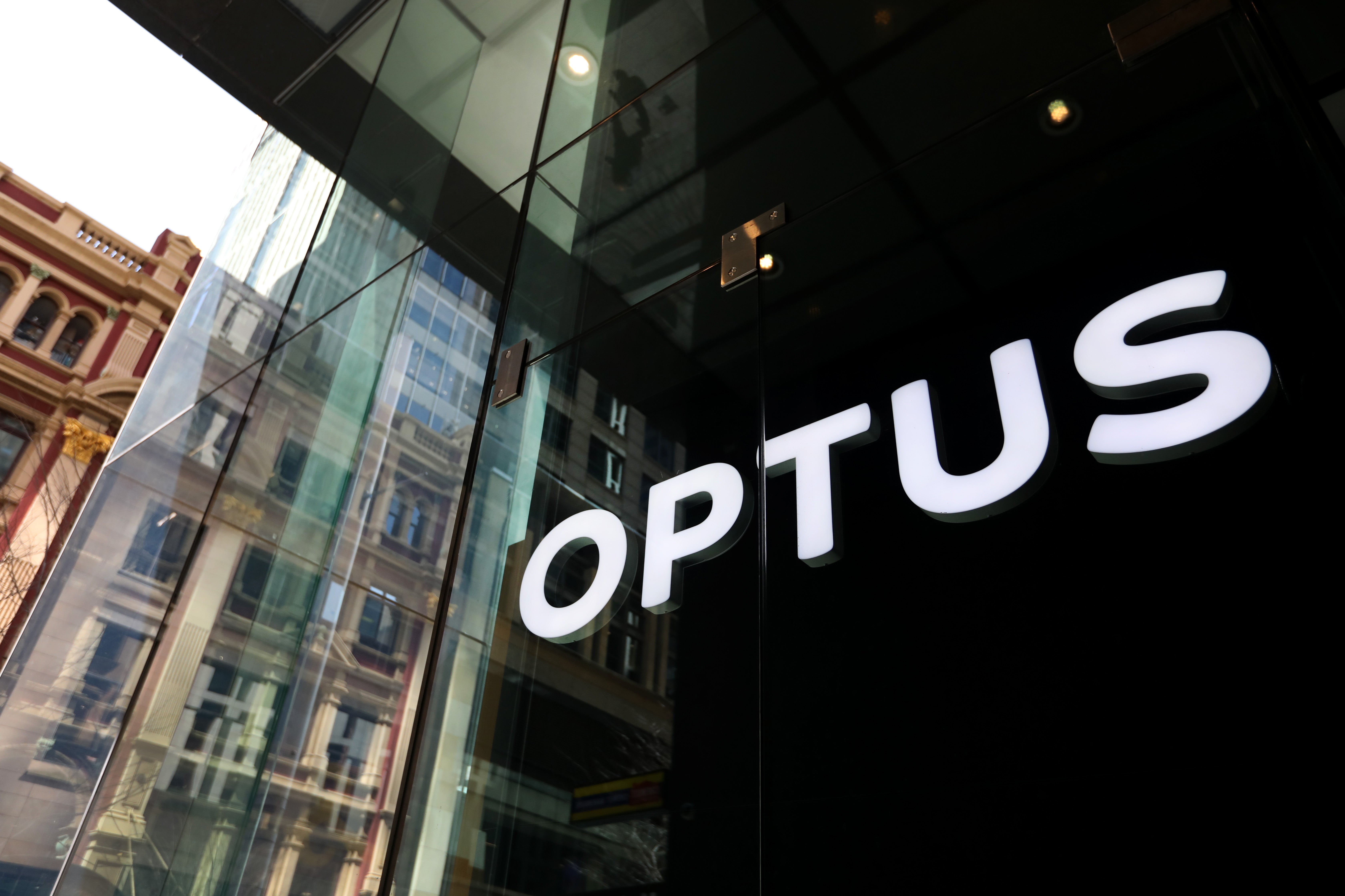 <p>The Optus company sign is displayed in a store window in the central business district on 23 September 2025 in Sydney, Australia. The recent Optus Triple-0 outage, caused by a failed network upgrade, blocked around 600 emergency calls across parts of Australia and has been linked to several deaths, sparking public outrage and fierce political condemnation</p>