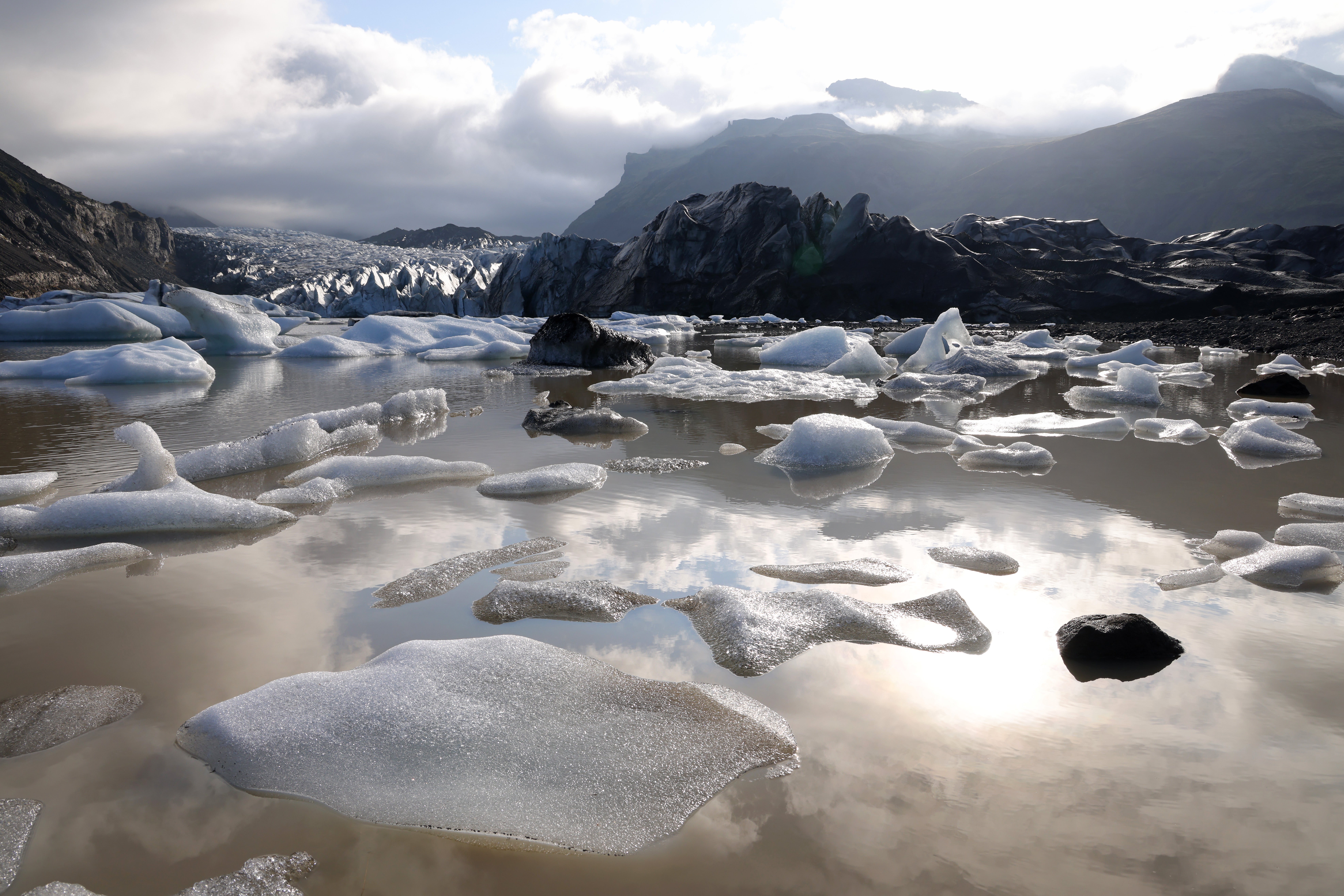Ice from Svinafellsjokull glacier floats in a lake of meltwater as the glacier looms behind near Svinafell, Iceland