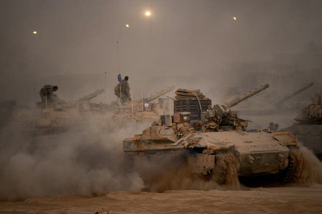 Israeli soldiers drive a tank along the Israeli-Gaza border after Israel and Hamas agreed to a pause in their war (Emilio Morenatti/AP)