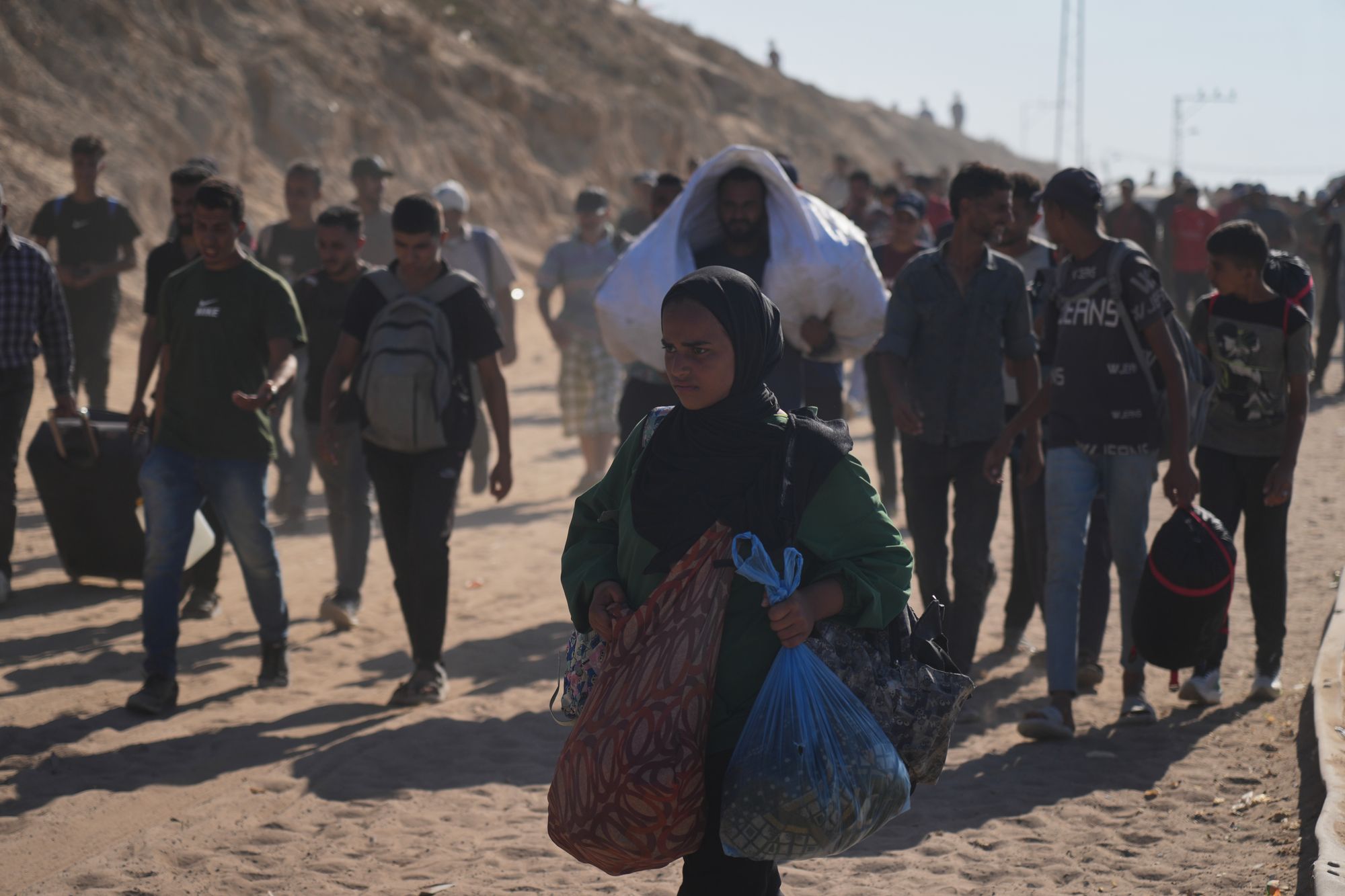 Displaced Palestinians walking with their belongings near Wadi Gaza