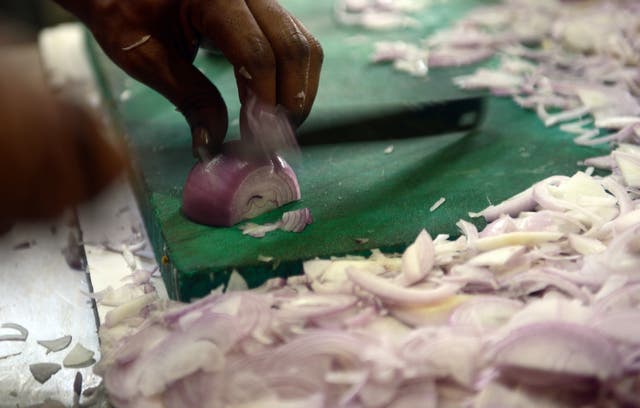 <p>Indian cook chopping onions in the kitchen</p>