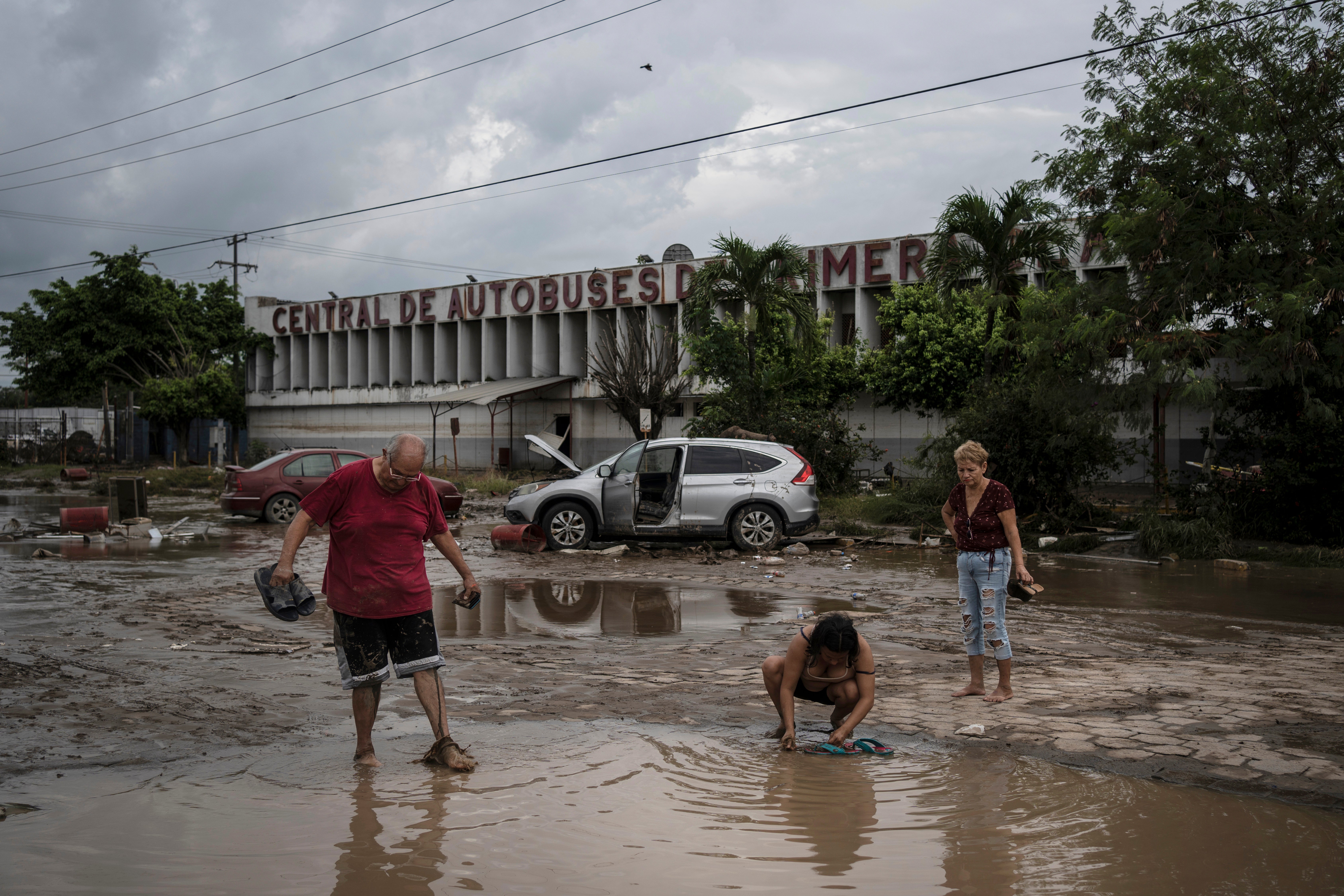 <p>Residents walk past a damaged bus station after heavy rainfall in Poza Rica, Mexico, on 11 October 2025</p>