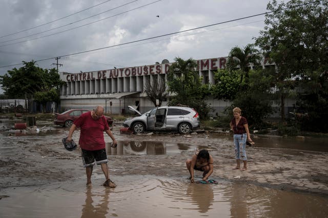 <p>Residents walk past a damaged bus station after heavy rainfall in Poza Rica, Mexico, on 11 October 2025</p>