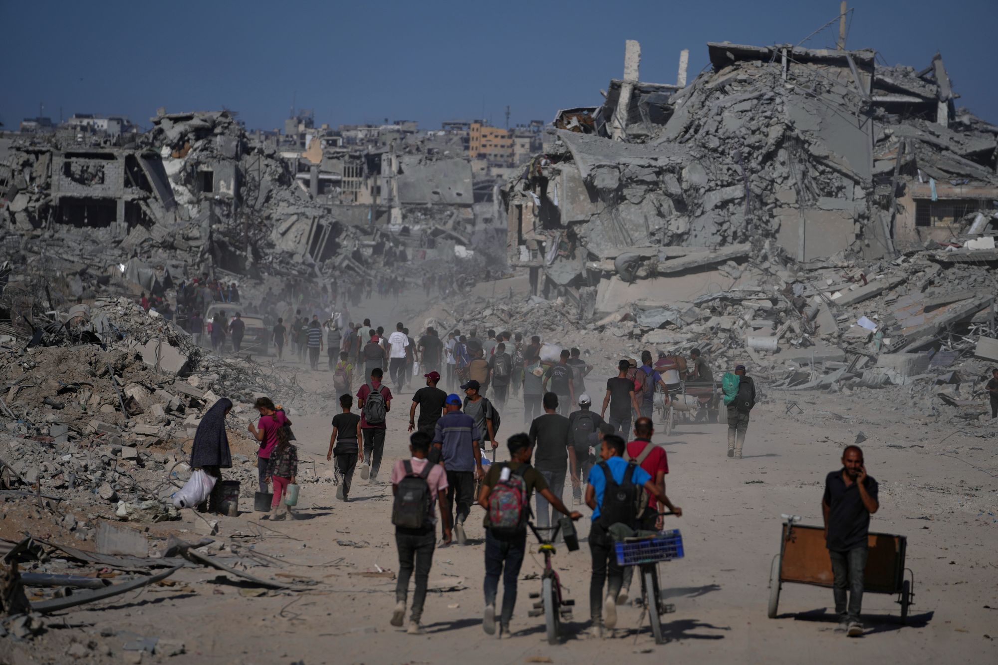 <p>Displaced Palestinians walk past destroyed buildings as they return to their homes in the Zeitoun neighborhood of Gaza City</p>