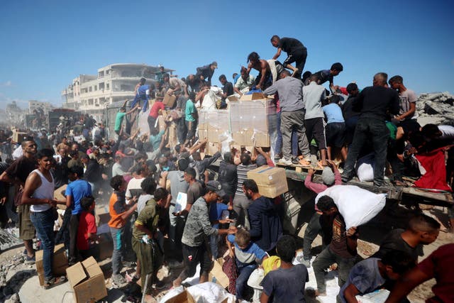 <p>Palestinians collect aid parcels from aid trucks which entered from the Karem Abu Salem crossing, in Khan Yunis in the southern Gaza Strip</p>