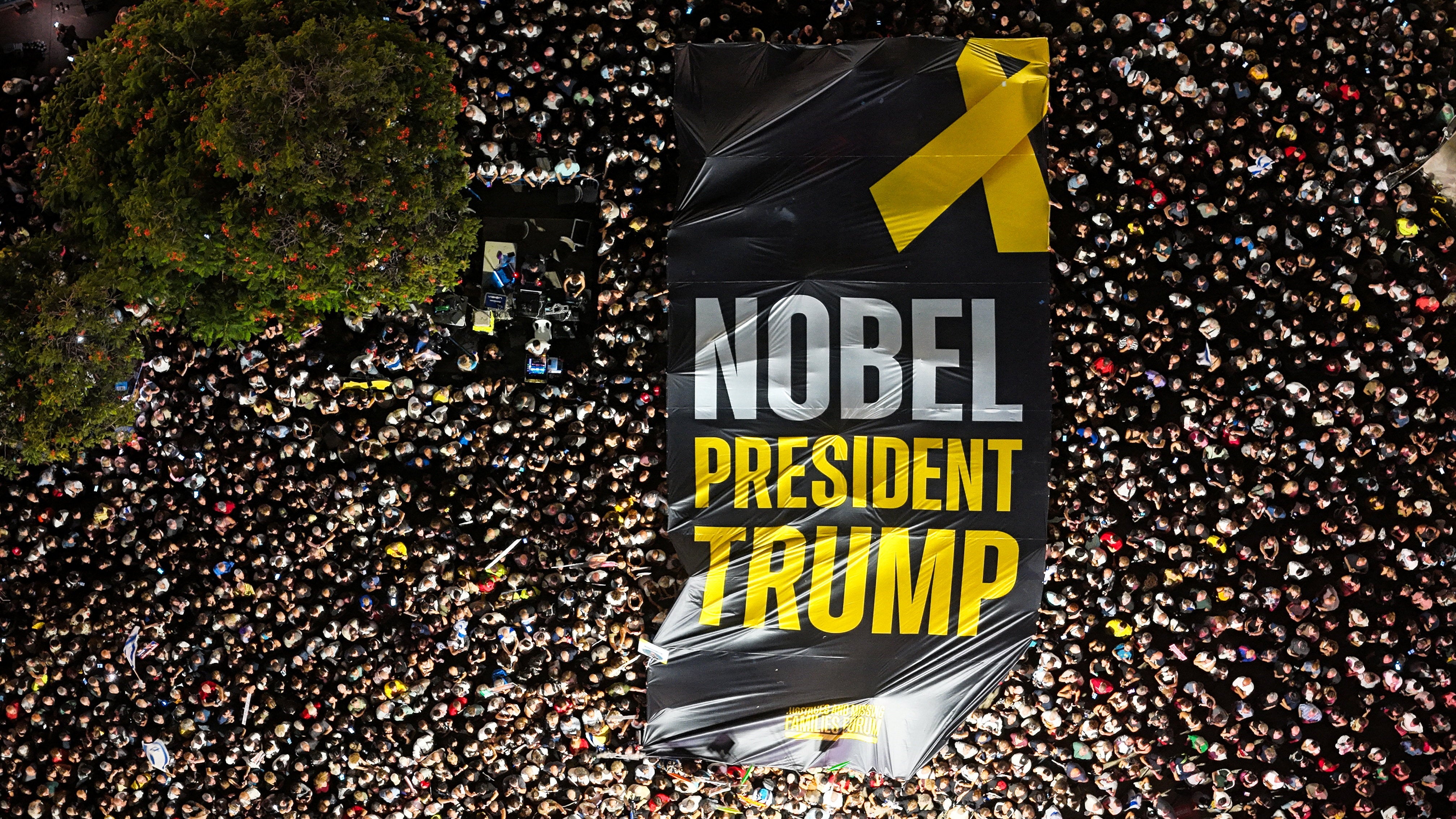A drone photo of people gathering in Hostages Square as they hold up a giant sign calling for Donald Trump’s efforts to be rewarded with Nobel Peace Prize