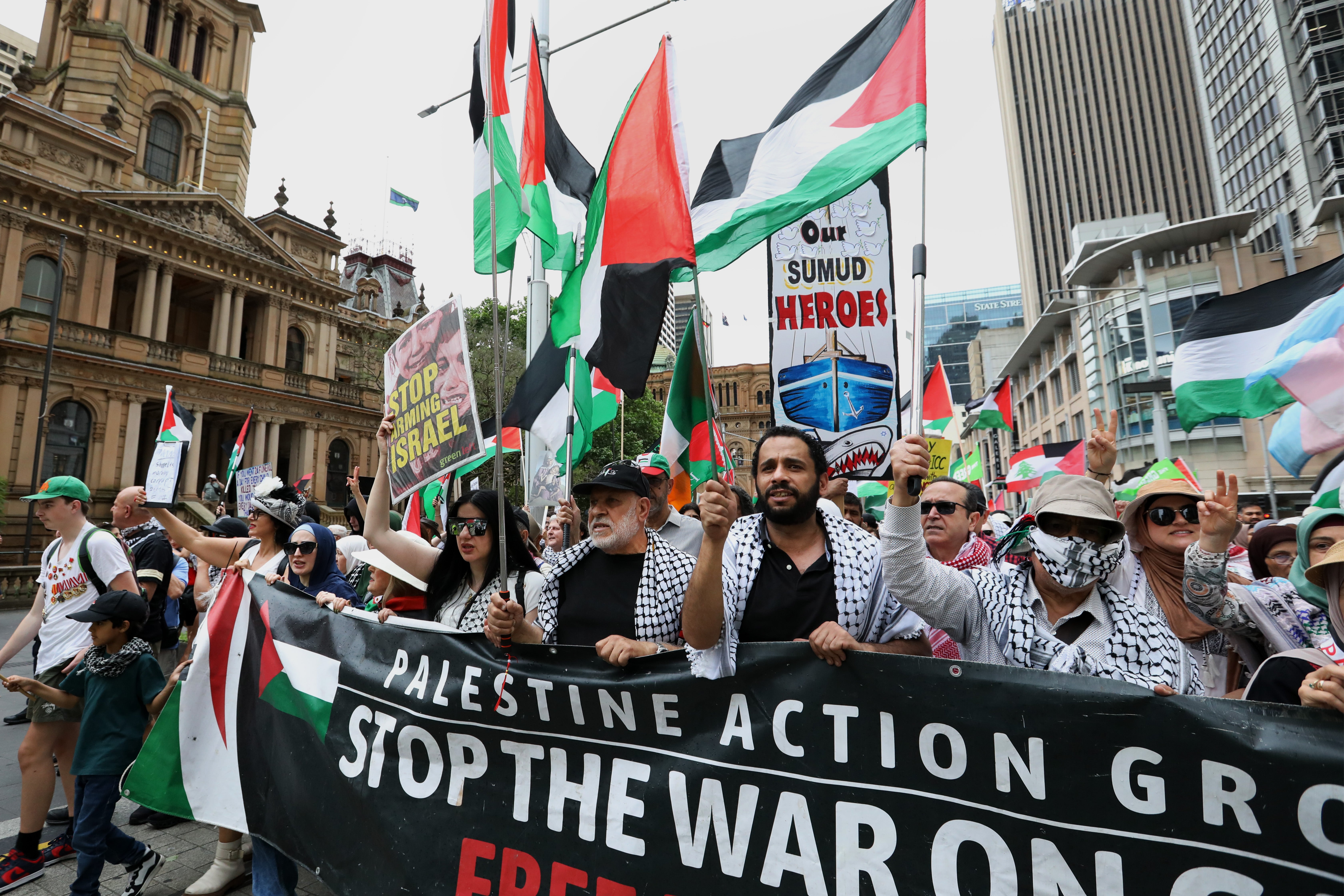 Demonstrators hold flags and placards as they move along George Street during a rally for Gaza