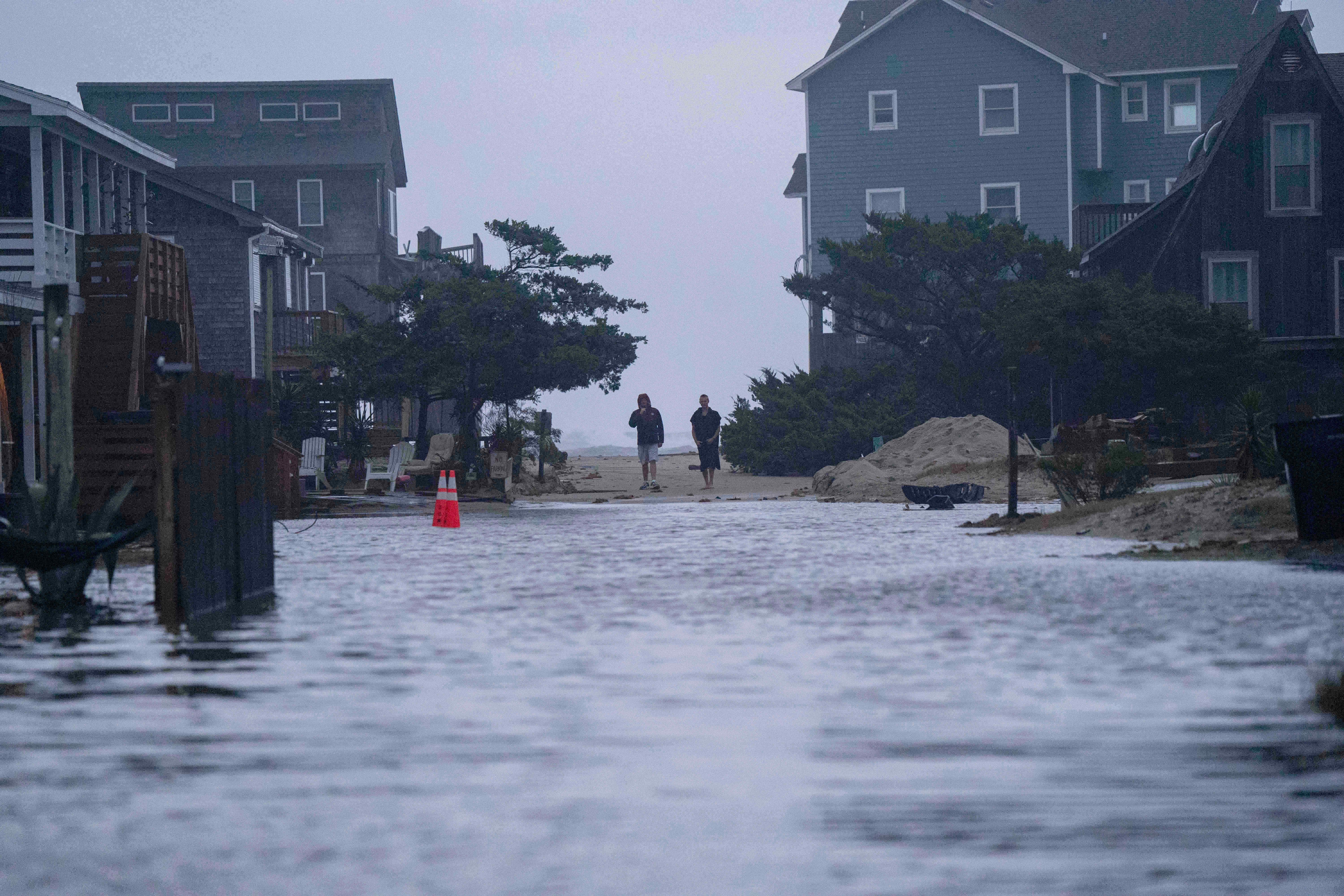People look out at a flooded road in the midst of a storm in North Carolina, where the Nor’easter first slammed the U.S.