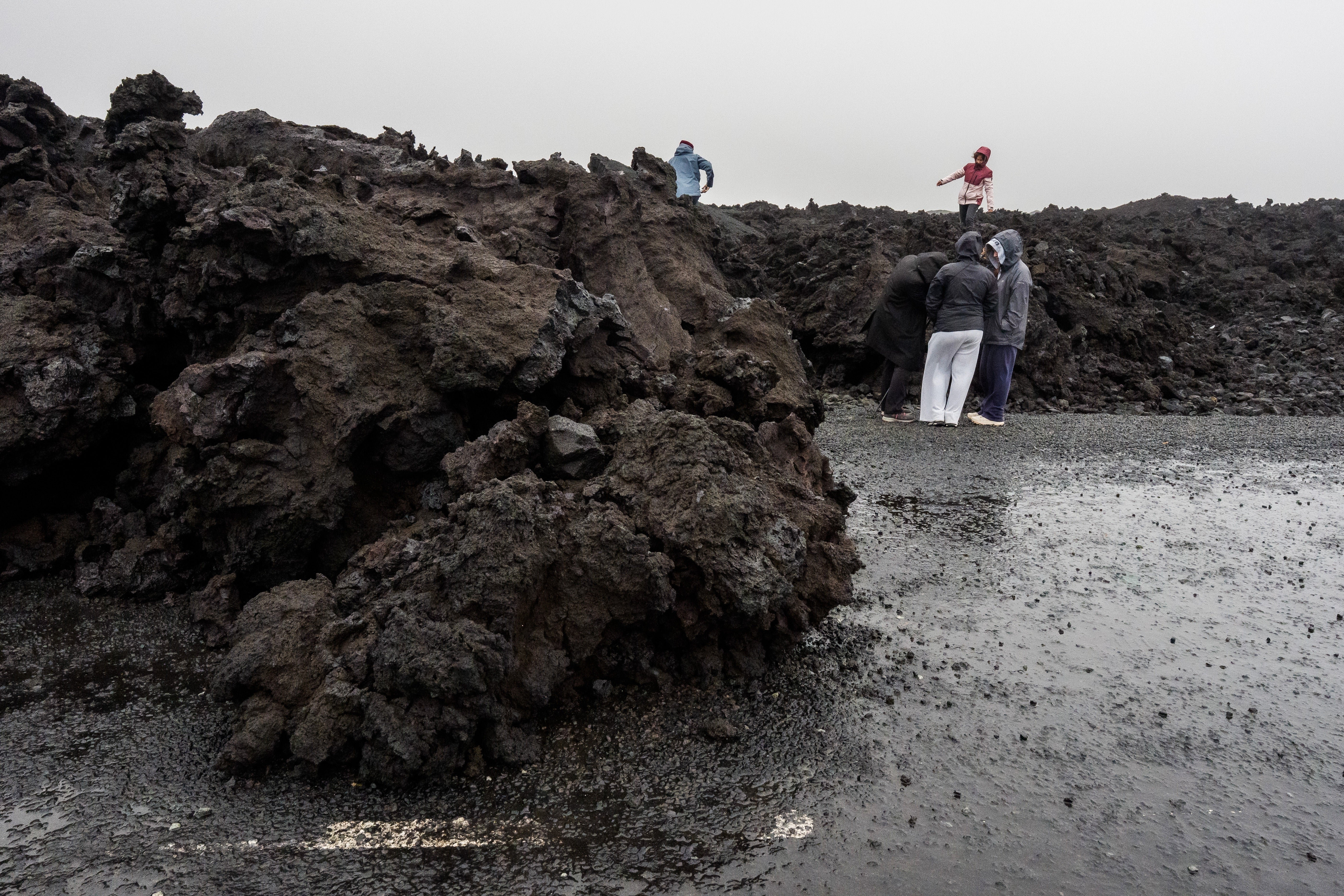 Visitors stand at the edge of lava flows outside Grindavik, Iceland, Monday, Oct. 13, 2025. (AP Photo/Marco di Marco)