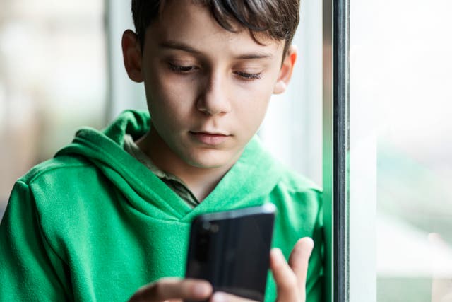 <p>Boy with smartphone indoors. Preteen boy using a phone checking social media. Concept of children using the smartphone</p>