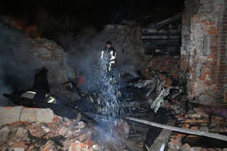 Ukrainian firefighters work amid to extinguish a smouldering building in a fire following Russian strikes in Kharkiv