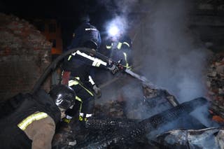 Ukrainian firefighters work amid to extinguish a smouldering building in a fire following Russian strikes in Kharkiv