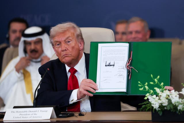 <p>Donald Trump holds the signed agreement that will bring the war in Gaza to an end at a summit in Sharm el-Sheikh in Egypt</p>