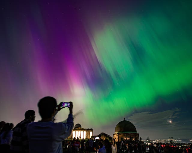 <p>Spectators on Calton Hill in Edinburgh, UK, watch the northern lights</p>