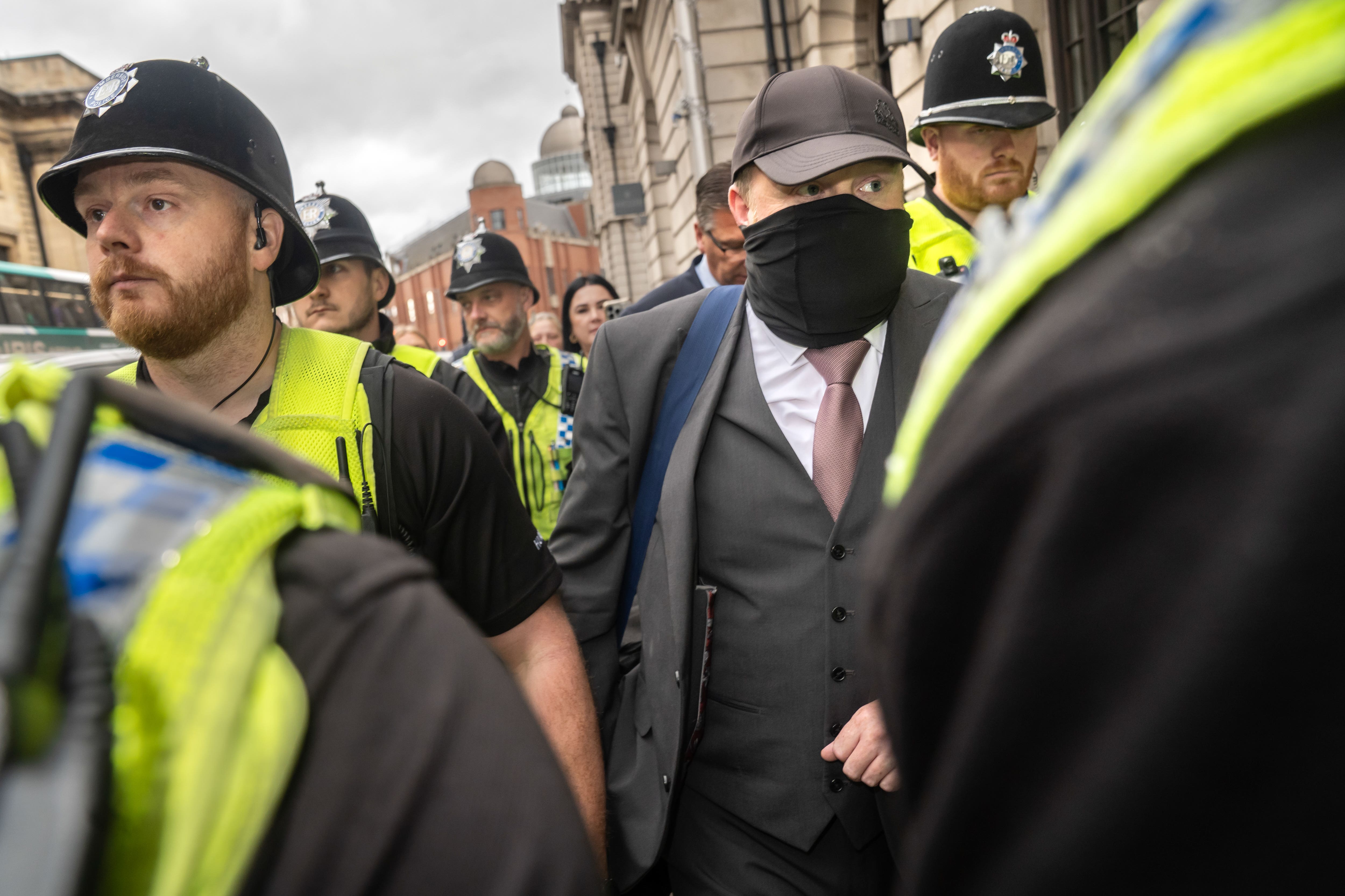 Former funeral director Robert Bush, with a mask and a mauve tie, leaves Hull Crown Court accompanied by police officers (Danny Lawson/PA)