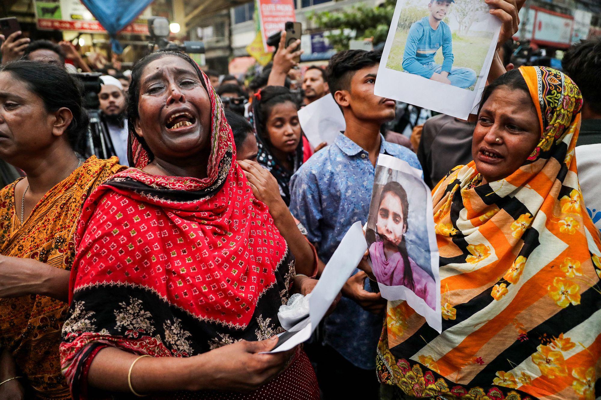 Relatives wail as they hold pictures of fire accident victims in Dhaka on Wednesday