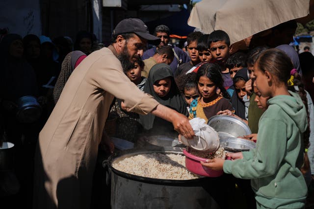 <p>Palestinian children receive food in Deir al-Balah</p>