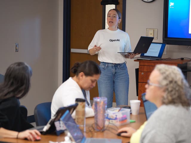 <p>Natalie Cone, head of OpenAI Forum, center, speaks with attendees during a Microsoft AI skilling event</p>