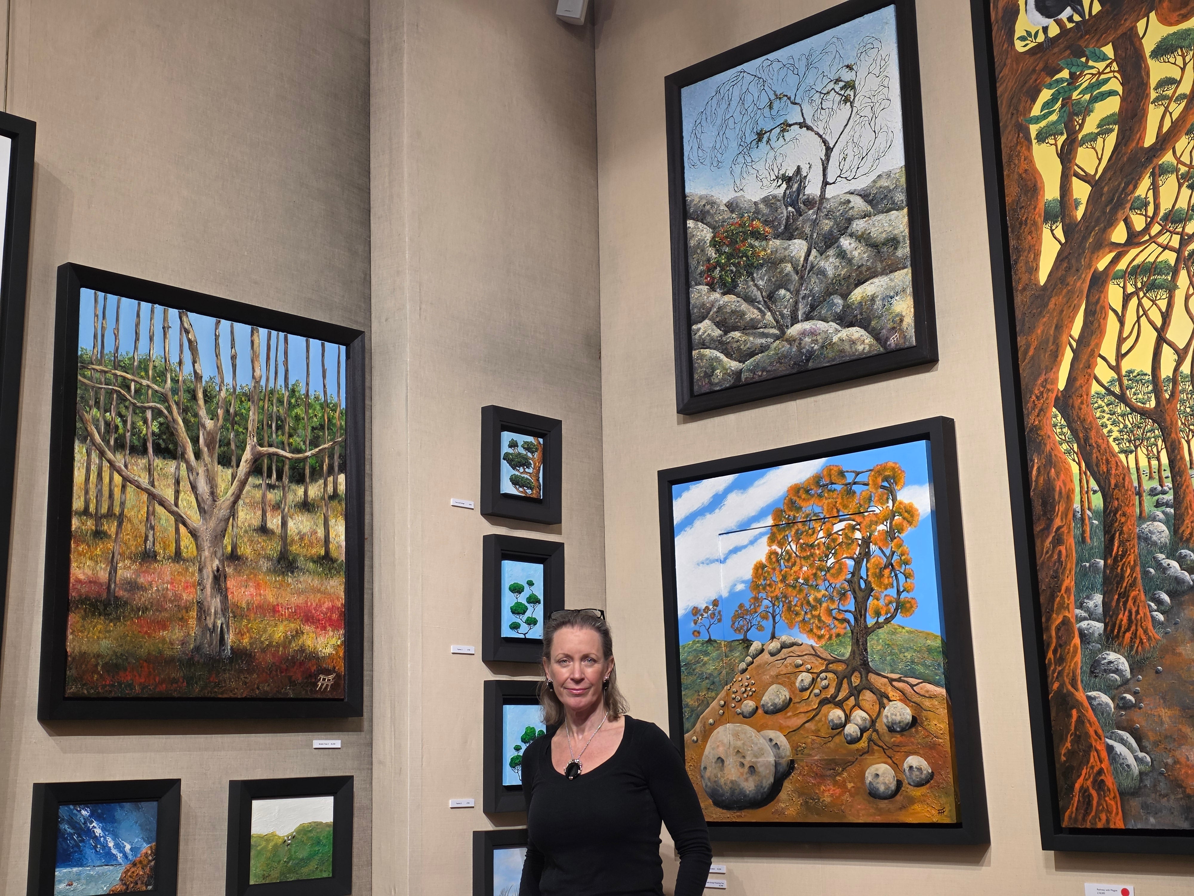 <p>Frieda Hughes, surrounded by her paintings mounted in a gallery</p>