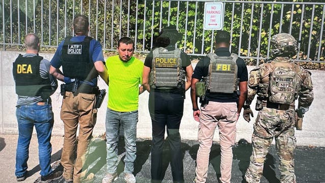 <p>Police pose with Juan Espinoza-Martinez, whom officials allege is a Latin Kings gang member who called for the killing of Gregory Bovino, a top Border Patrol official</p>