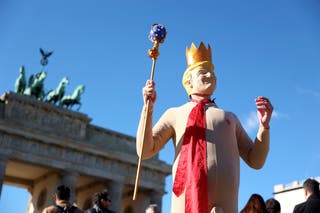 A demonstrator wears a mask depicting U.S. President Donald Trump during a 