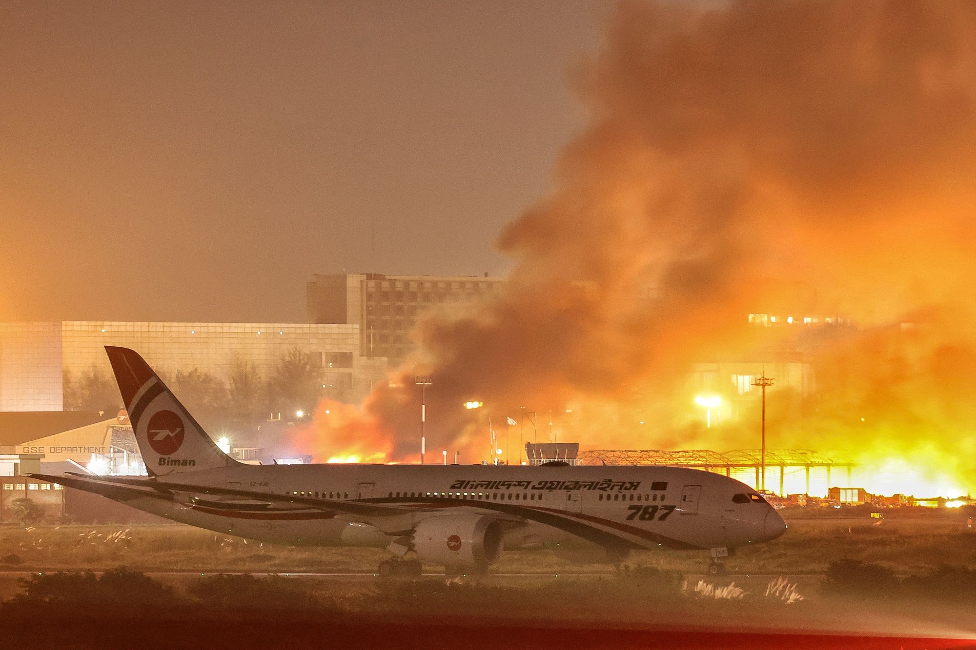 A plane sits on the tarmac as firefighters battle the blaze