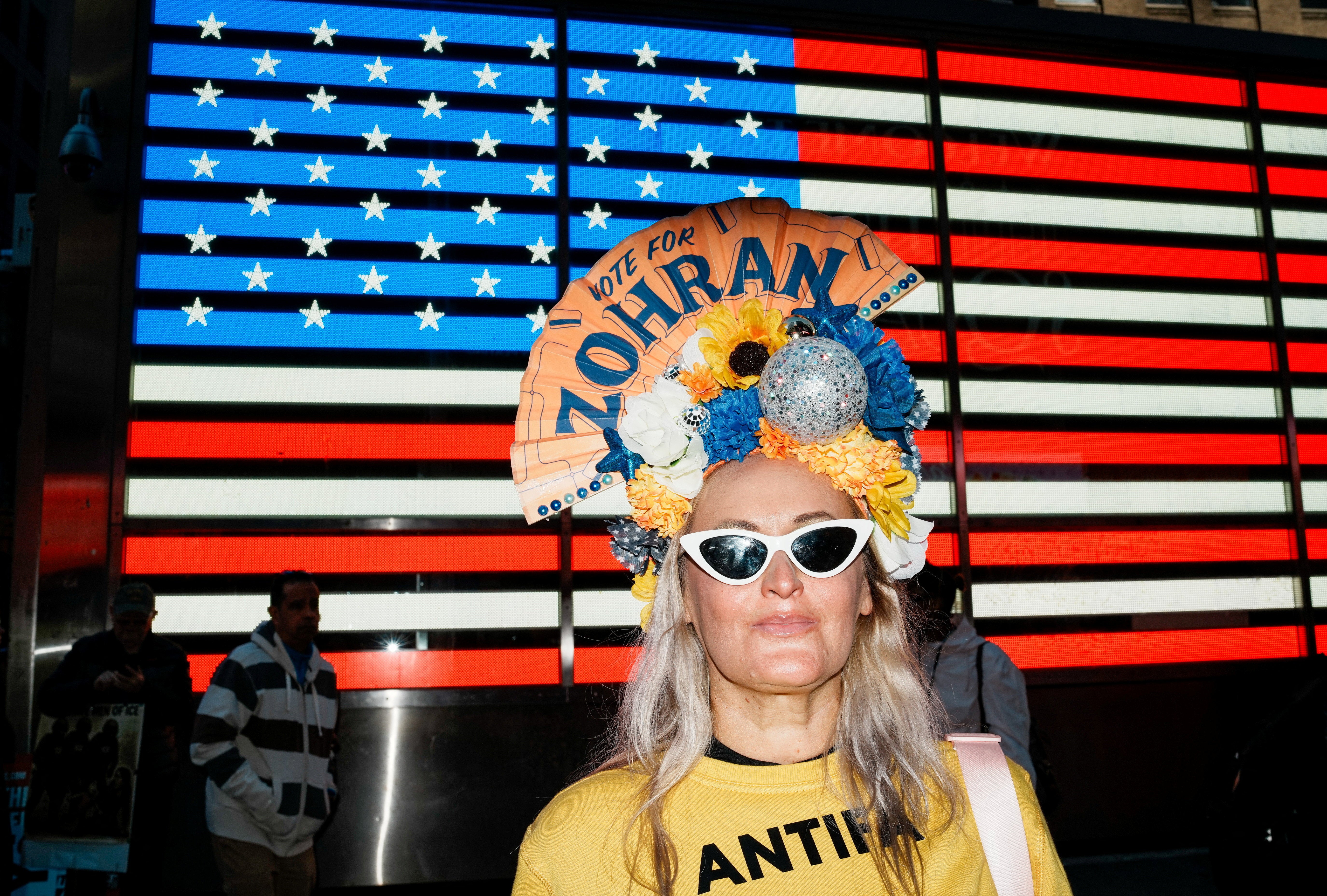 A woman wearing an ‘Antifa shirt and a fan on her head with a message in support of New York City mayoral candidate Zohran Mamdani