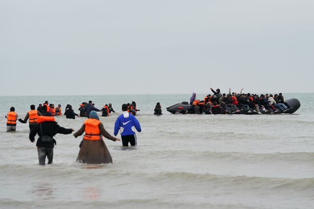 <p>People thought to be migrants wade into the sea to board a small boat in Gravelines, France, on October 10 </p>