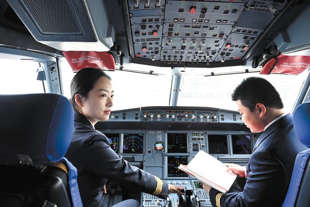 <p>Captain Gu Xinyue (left) makes flight preparations in the cockpit of an aircraft in Hefei, Anhui province, in March last year</p>