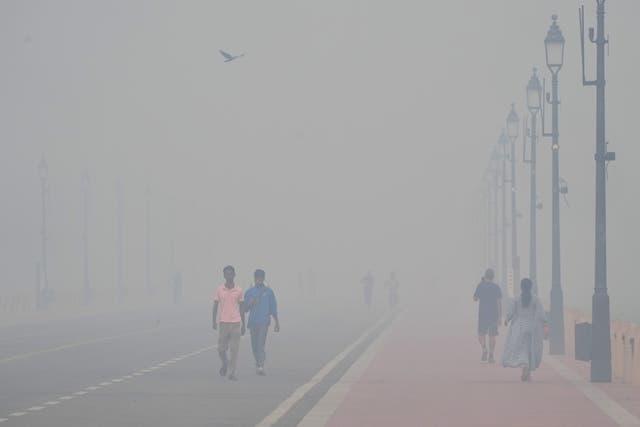 <p>People walk amid morning smog near India Gate amid a day after Diwali in Delhi, India</p>