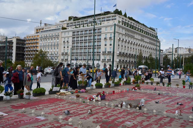 <p>People stand in the square where the names of 57 victims of Greece's deadliest train crash are written on the ground, as Parliament debates regulations to protect the Tomb of the Unknown Soldier monument, which has recently been the focus of demonstrations by victims' relatives. (AP Photo/Petros Giannakouris)</p>