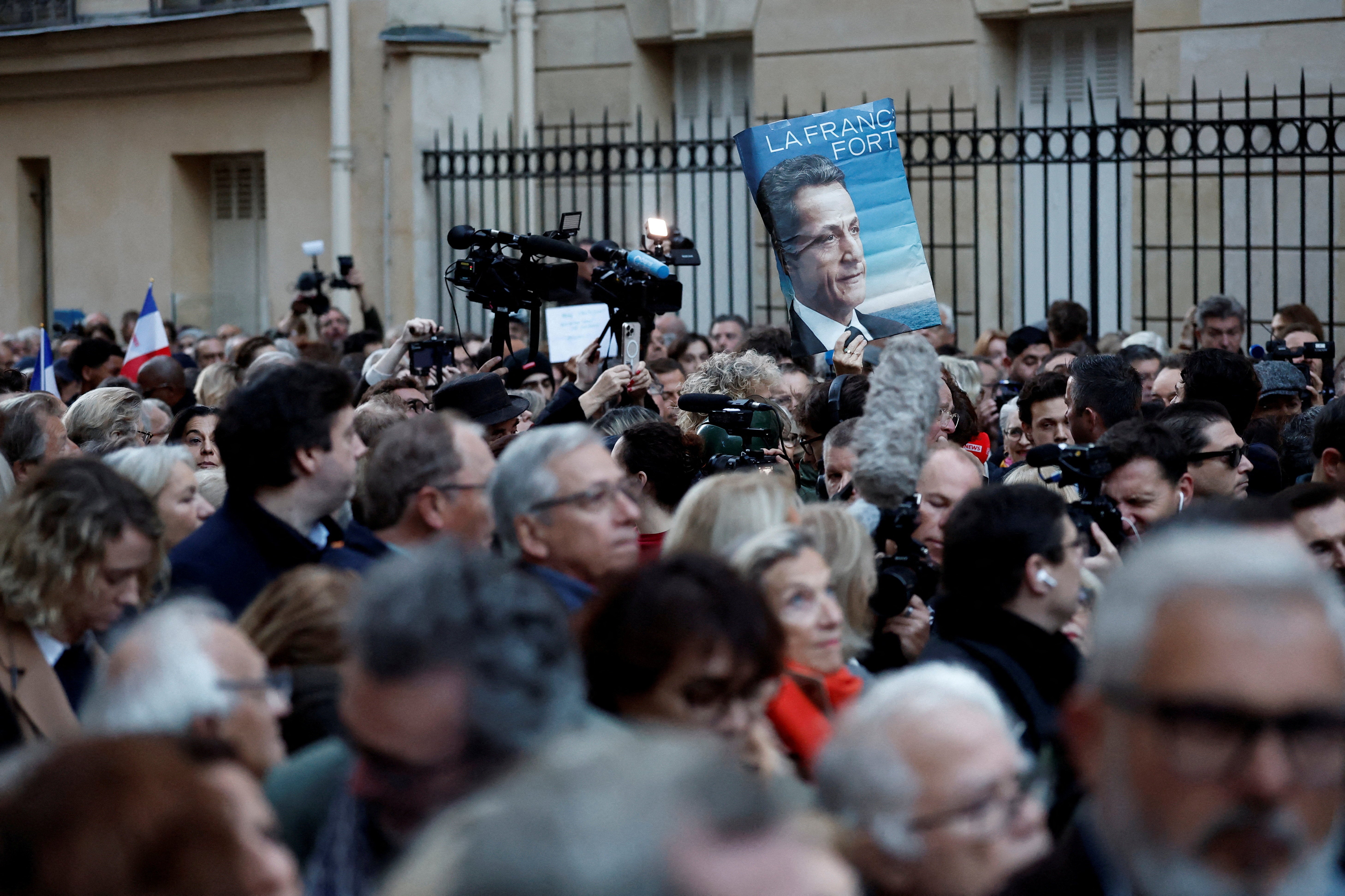 A supporter holds a poster with a portrait of Nicolas Sarkozy and the slogan 